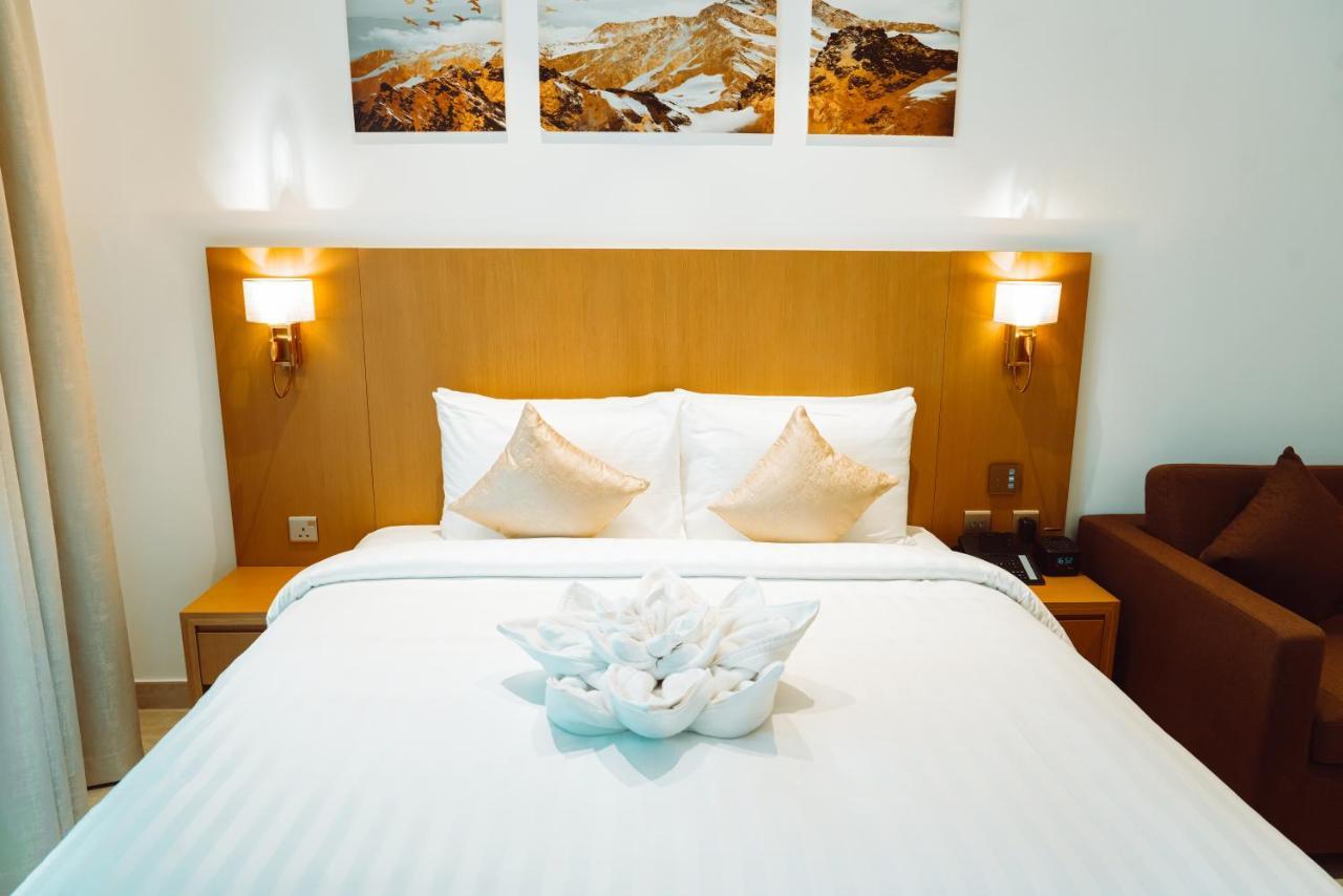 He Hotel Apartments Dubai Ruang foto A bed with a bedsheet